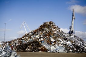 Heap of metal scrap at junkyard against blue sky